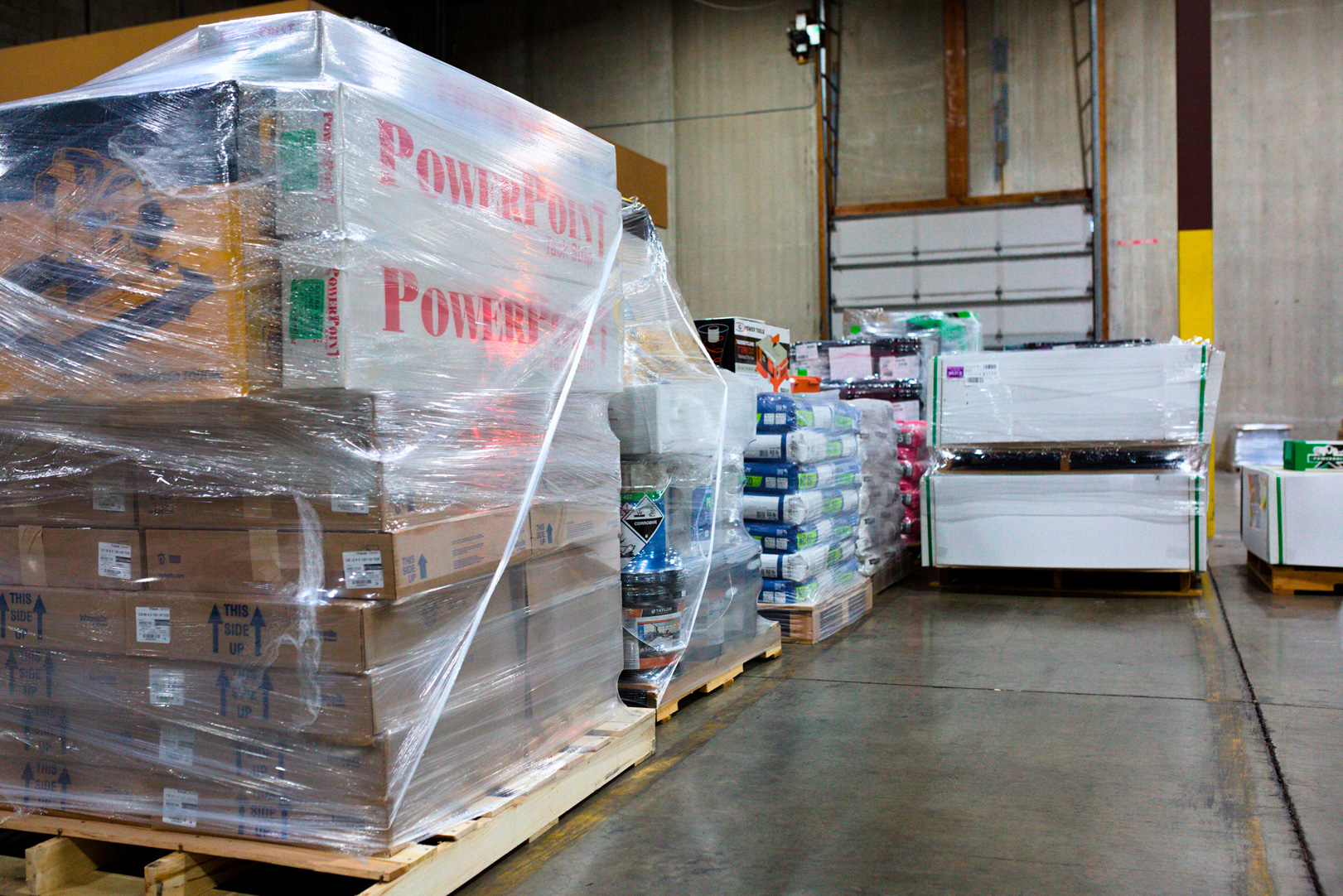Pallets wrapped in plastic with boxes and construction materials.