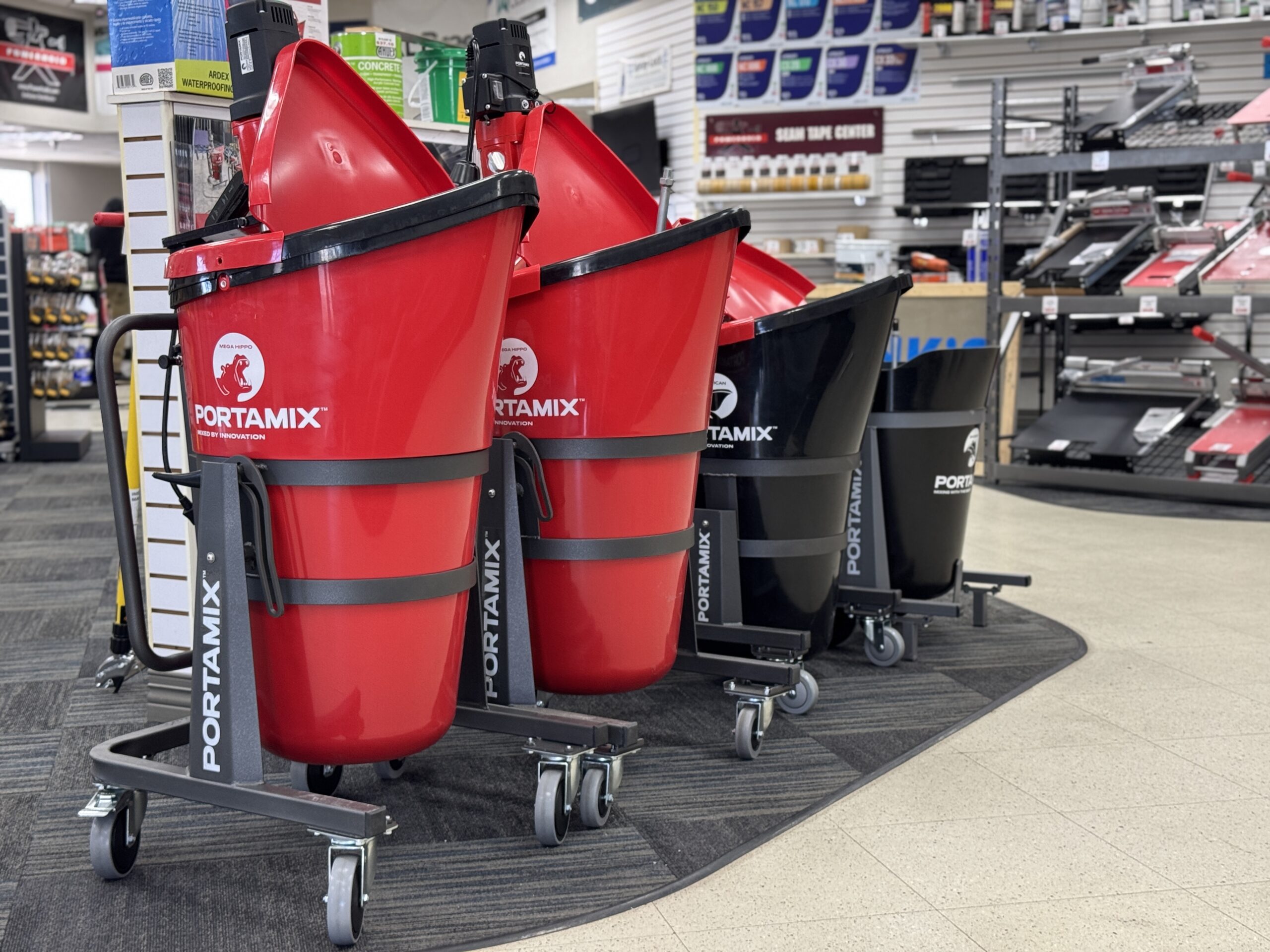 Display of red and black PORTAMIX mixers on wheels inside a showroom.