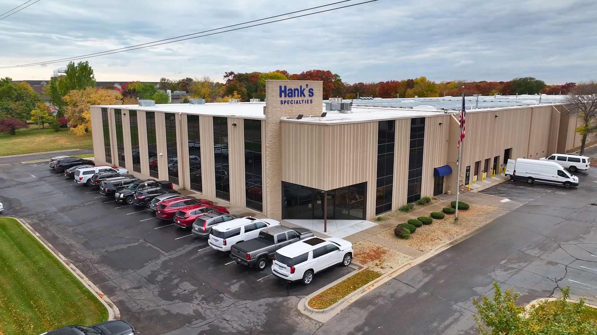 Hank's Specialties headquarters with parking lot and surrounding trees in autumn.